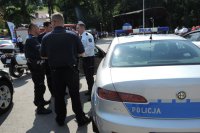Niemiecki policjant i kilku polskich policjantów przed radiowozem służbowym