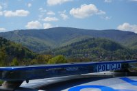 napis policja na dachu radiowozu, a w tle widok na góry