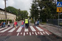 policjant uczy dzieci bezpiecznego korzystania z przejść dla pieszych