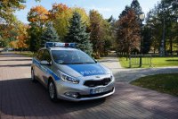 radiowóz policyjny, a w tle widok na drzewa w wiślańskim parku - jesienna pora roku