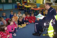 Policjant w przedszkolu czyta dzieciom książkę