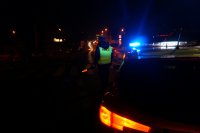 Policjant przy radiowozie zatrzymuje pojazdy do kontroli w nocy