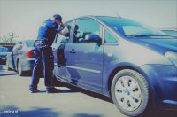 policjant sprawdza czy w zaparkowanym samochodzie są dzieci narażone na przegrzanie