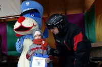 Policjant patrol narciarskiego wręcza nagrodę dla dziewczynki- uczestniczki konkursu