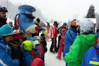 Zdjęcia ze spotkania z dziećmi na lodowisku w Cieszynie- na tafli lodowiska policjant, dzieci oraz pies Sznupek-maskotka śląskiej Policji