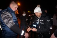 Kajetan Kajetanowicz i policjant rozdają odblaskowe elementy