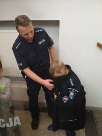 policjant z dziećmi , które ubierają i przymierzają policyjny sprzęt