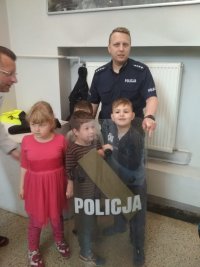 policjant z dziećmi , które ubierają i przymierzają policyjny sprzęt