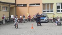 policjant przeprowadza egzamin na kartę rowerową, dziecko jedzie na rowerze, policjant ocenia