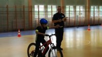 policjant przeprowadza egzamin na kartę rowerową, dziecko jedzie na rowerze, policjant ocenia