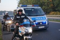 policjanci na motocyklach, za nimi radiowóz policyjny