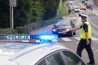 policjant zatrzymuje auto do kontroli, unosi tarczę i daje znak do zjechania