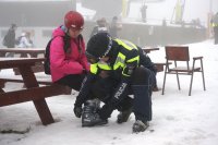 policjant pomaga zapiąć but narciarski dziecku