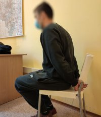 zatrzymany mężczyzna siedzi na krześle, ręce z tyły spięta kajdankami