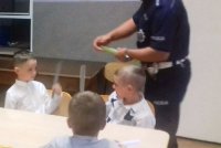 policjant wręcza odlaski dzieciom