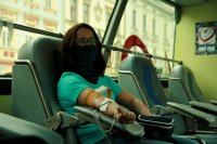 grafika- kobieta oddaje krew- siedzi i ma wyciągniętą rękę
