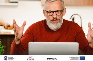 zdjęcie-mężczyzna siedzi przed laptopem, patrzy w w ekran i gestykuluje