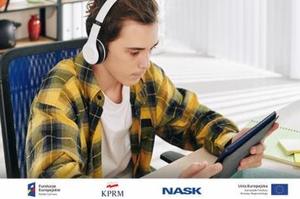 zdjęcie-chłopak ze słuchawkami na uszach, siedzi i patrzy w tablet